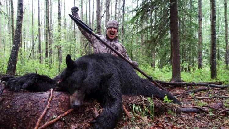 Bowmar and body of bear he butchered (Image: YouTube)